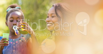 Mother and daughter blowing bubbles with peach bokeh transition