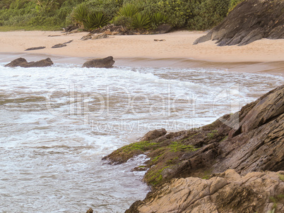 Deserted beach with waves crashing on the rocks