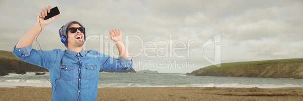 Millennial man in headphones dancing on overcast beach