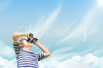 Boy looking through binoculars against sky