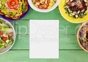Blank card on green wooden desk with food and copy space on paper