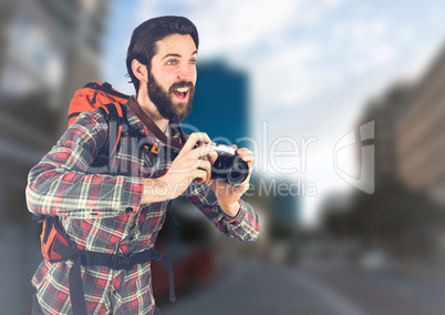 Millennial backpacker with camera against blurry street