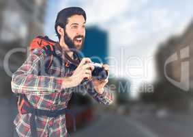 Millennial backpacker with camera against blurry street