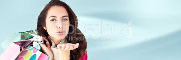 Shopper with bags and blowing kiss against blurry blue abstract background 3d