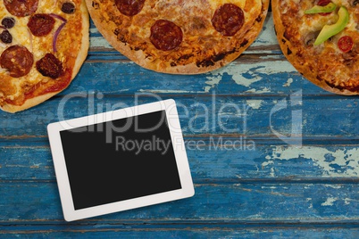 Tablet on blue wooden desk with food and copy space