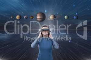 Woman in VR headset looking up to 3D planets against blue sky with flare