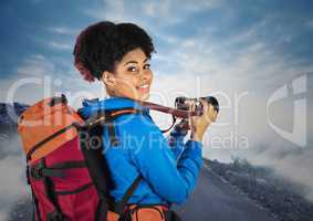 Millennial backpacker with camera against misty road