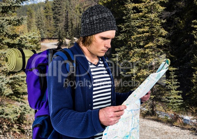Millennial backpacker with map against blurry trees