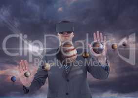 Man in VR headset touching 3D planets against purple sky with clouds and flares