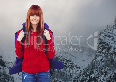 Millennial backpacker smiling against snowy mountains