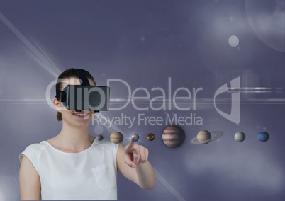 Woman in VR headset touching 3D planets with flares against purple background