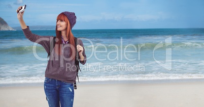 Millennial backpacker taking selfie against beach