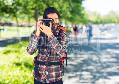 Millennial backpacker with camera against blurry campus