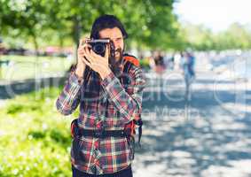 Millennial backpacker with camera against blurry campus