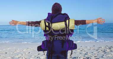 Back of millennial backpacker against beach