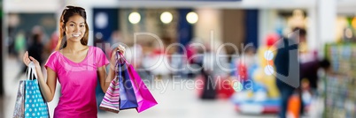 Shopper smiling with bags in blurry shopping centre