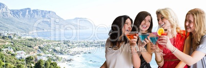 Women with cocktails against blurry coastline