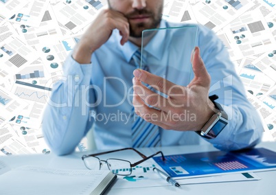 Business man with glass tablet at desk against documents backdrop