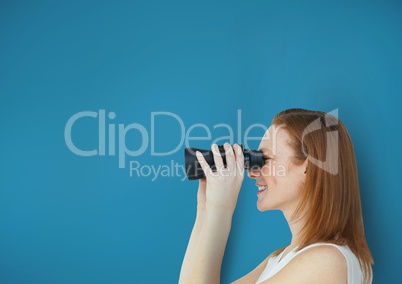 Happy woman looking through binoculars against blue background