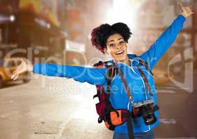Millennial backpacker arms out against blurry street with flare