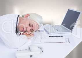 Doctor asleep at desk against white blurred hallway