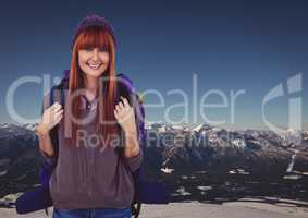 Millennial backpacker smiling against snowy mountain range
