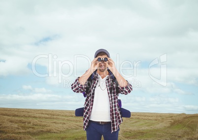 Man looking through binoculars against landscape background