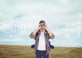 Man looking through binoculars against landscape background