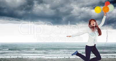 Woman with balloons celebrating on grey beach