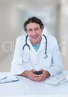 Doctor at desk with phone against blurred hallway