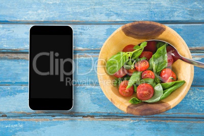 Phone on blue wooden desk with food and copy space on mobile phone