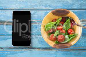 Phone on blue wooden desk with food and copy space on mobile phone