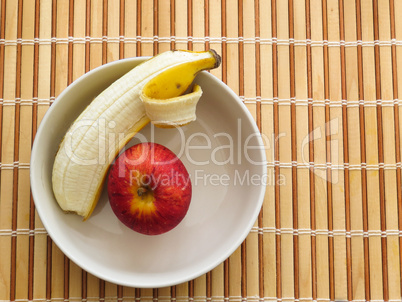 Apple and banana inside bowl on wooden table