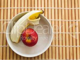 Apple and banana inside bowl on wooden table