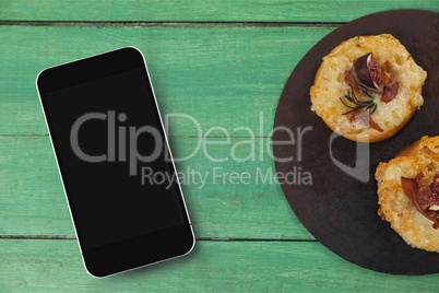 Phone on green wooden desk with food and copy space on mobile phone