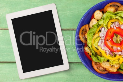 Tablet on green wooden desk with food 3d