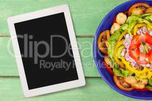 Tablet on green wooden desk with food 3d