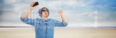 Millennial man in headphones dancing on beach
