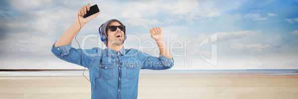 Millennial man in headphones dancing on beach