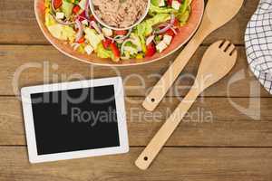 Tablet on wooden desk with food and copy space