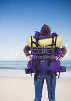 Back of millennial backpacker looking at beach