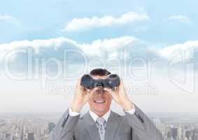 Happy man looking through binoculars against city background