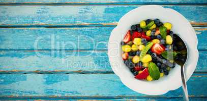 Fresh salad in bowl on blue wooden table