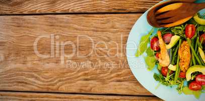 Fresh salad in blue plate on brown wooden table