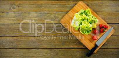 Lettuce and tomatoes on wooden cutting board