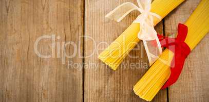 Raw spaghetti tied with ribbons on wooden table