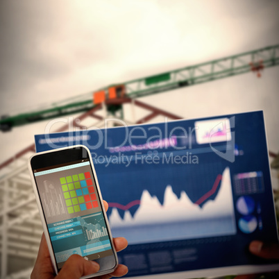 Composite 3d image of cropped image of hand holding mobile phone and graph