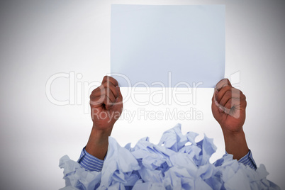 Composite image of heap of crumpled paper with hand holding blank page