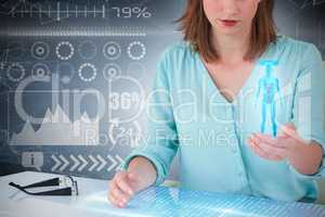 Composite 3d image of businesswoman sitting at desk and using digital screen