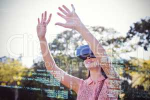 Smiling woman raising her hands while using a VR 3d headset in the park